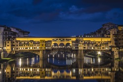Ponte Vecchio In Florence, Italy With Water  Reflection At Night