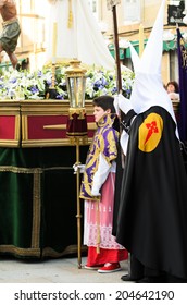 Pontevedra, SPAIN - APRIL 17, 2014: A Boy Dressed Acolyte Wait Between Hooded, To March In The Procession Of Holy Week.