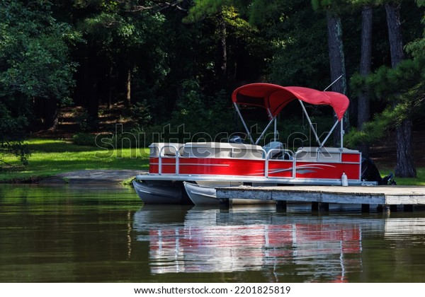 Pontoon boat at private\
dock on lake.