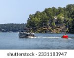 Pontoon boat pulling inflatable tube float raft on lake. Family on a pontoon party boat enjoying tubing on a summer day with their children.