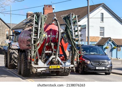 Pontyclun, Wales - March 2022: Large Farm Tractor Towing Farm Spraying Equipment Passing A Car On The Main Road Through The Village Of Pontyclun In South Wales.