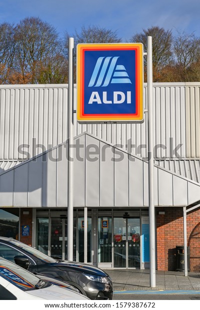 PONTYPRIDD, WALES - DECEMBER 2019: Sign above\
the entrance of the ALDI supermarket in Upper Boat near Pontyrpidd\
with cars parked\
outside.