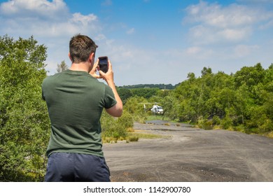 PONTYPRIDD, WALES - JULY 2018: Person Taking A Picture With A Camera Phone Of A Helicopter Hovering Over A Pond To Fill A Water Bucket. The Helicopter Was Used To Fight A Grass Fire In Pontypridd.