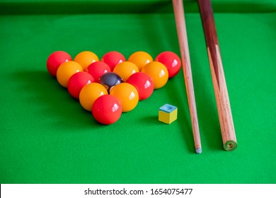 Pool Balls, Cue Chalk And Wooden Pool Cue On The Green Felt Of A Pool Table