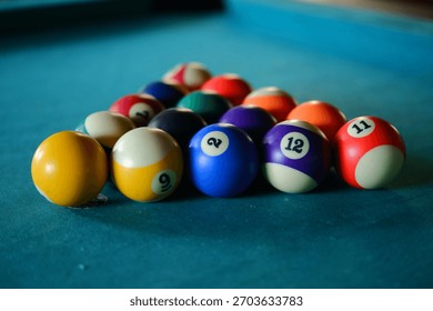 Pool balls racked up in a triangular formation on a blue billiard table, captured with a shallow depth of field