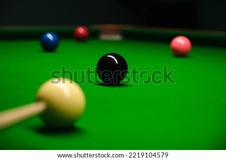 Pool, billiard, snooker balls from a low angle on soft green textured table. For a dynamic design element on a wallpaper, background, banner, poster at a party, club, bar or pub.