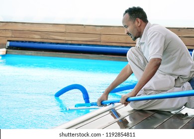 Pool cleaner during his work. Hotel staff worker cleaning the pool.