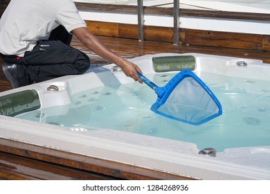 Pool cleaner during his work. African hotel staff worker cleaning the pool.