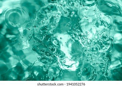 Pool, hot tub water background. Ripples on toned turquoise in transparent water in swimming pool with light reflection. Top view.