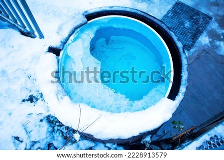 a pool with ice water. ice in the tub. font on the street in winter. a barrel of water for bathing in winter