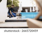 Pool maintenance worker checking the automatic pool covering system with a smartphone, ensuring optimal functionality and safety during summer days