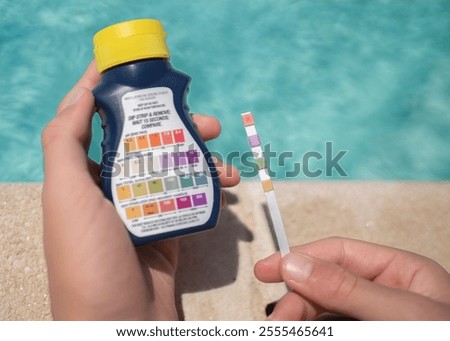 Pool maintenance worker checking water quality with test strip and reagents