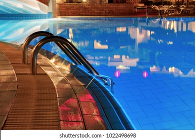 Pool At Night. Blue Water And Handrails To Enter The Water.