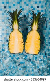 In the pool on the water float two halves of the cut pineapple. Tropical fruits, healthy food, summer, top view