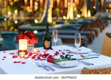 Pool side Candlelight Dinner and Romantic Sunset Dining table setup for couple with bottle of champagne