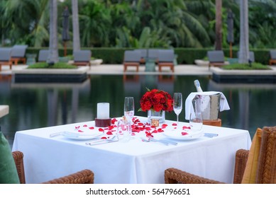 Pool side Candlelight Dinner and Romantic Sunset Dining table setup for couple with bottle of champagne