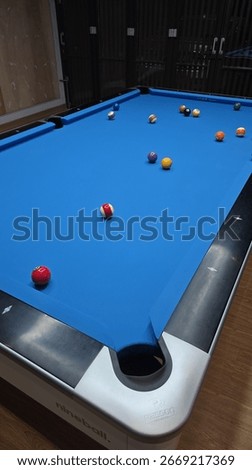 Pool table with all the billiard ball on a blue rasson ox table inside a private house