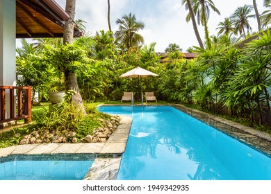 Pool With Umbrella And Beach Beds At Tropical Hotel Or Vacation Home. Beautiful Swimming Pool In Courtyard Of Residential House. Landscape Design Of Backyard. Nice Landscaping Garden In Summer Resort.