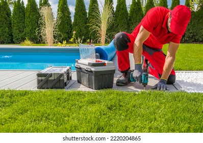 Poolside Composite Deck Installation Performed by Professional Worker. Residential Outdoor Swimming Pool Surrounding.