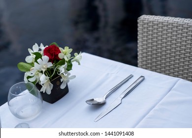 Poolside dining table for romantic date. Eating dinner by the pool is how married couple celebrate special occasion in romance way. The beautiful setting consists of flower, wine glass & candle.  - Powered by Shutterstock