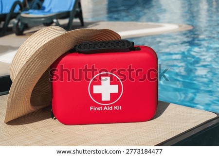 Poolside first aid kit with summer hat near resort water, vacation safety concept illustrating travel insurance, emergency preparedness, healthcare support, medicine assistance, protected leisure lifestyle