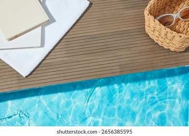 Poolside flat lay with notebook, sunglasses, and woven basket on wooden deck by blue water, ideal for summer product mockups and vacation scenes.