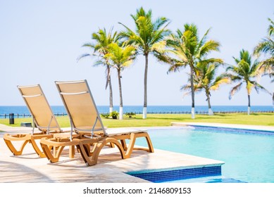 Poolside Lounge Beds On The Beach With A View Of The Ocean And Palm Trees