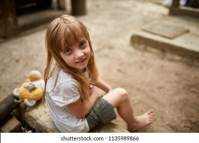 Poor Abandon Little Girl With Bare Feet Sitting In The Alley, View From Above