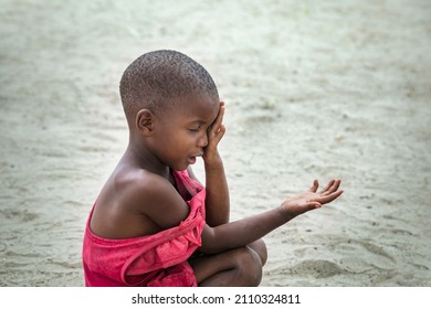 Poor African Child With A Red T-shirt And A Sad Face ,in A Village In Botswana Sitting In The Sand 