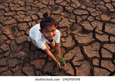 A poor asian  child a drought, sorrow, sits on a dry ground, hopes and drought.