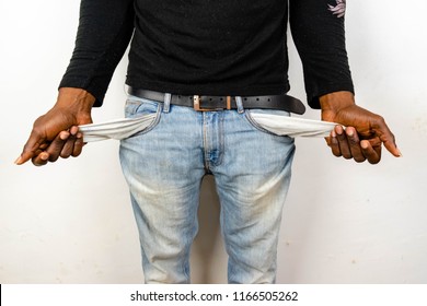 Poor Black man in jeans with empty pocket. Nigerian African American Man showing empty denim pockets on white background for jobless, broke, bankruptcy, bad credit, debt and financial trouble Concept.