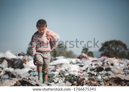 A poor boy collecting garbage waste from a landfill site in the outskirts .  children work at these sites to earn their livelihood. Poverty concept.