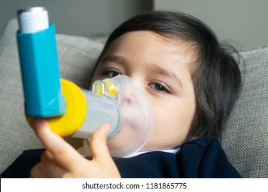 Poor Boy Have A Problem With Chest Coughing Holding Inhaler Mask,Child Using The Volumtic For Breathing Treatment,Kid Having Asthma Allergy Using The Asthma Inhaler,Healthcare And Medicine Concept

