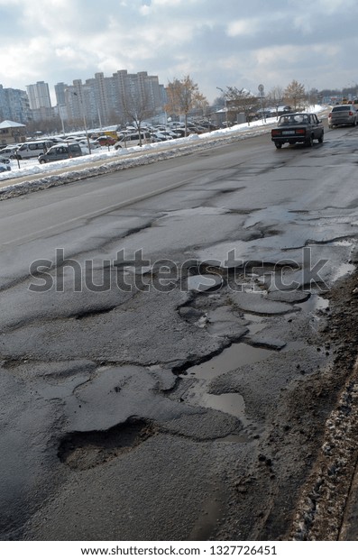 Poor condition of\
the road surface. Winter season. Hole in the asphalt, risk of\
movement by car, bad asphalt, dangerous road, potholes in asphalt.\
February 4, 2019.\
Kiev,Ukraine