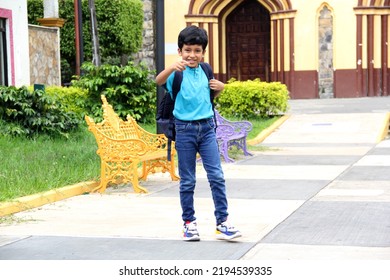 Poor Dark-haired 8-year-old Latin Boy Walks Down The Street On His Way To Study Back To School With A Backpack, The Family Makes An Economic Effort In Their Poverty To Buy The Books And Notebooks
