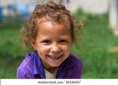 poor and dirty, but still happy and smiling cute little gypsy girl