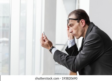 Poor eyesight Businessman trying to watch his phone display