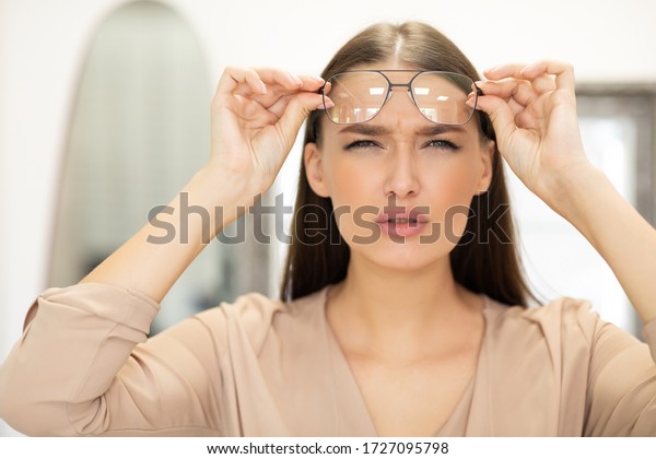 Poor\
Eyesight Concept. Portrait of beautiful young woman with spectacles\
squinting, trying to look closer, copy\
space