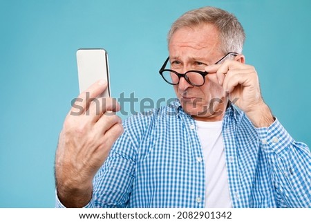 Poor Eyesight. Senior Man Squinting Eyes Reading Message On Phone Wearing Eyeglasses Having Problems With Vision, Blue Studio. Ophtalmic Issue, Bad Sight In Older Age, Macular Degeneration Concept