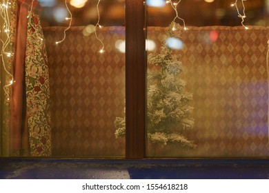 The Poor Family Is Preparing For The New Year And Christmas. Photography Of Small Decorative Artificial Christmas Tree In The Window.