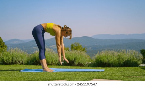 Poor forward bend flexibility for a young woman learning a basic yoga routine. Barefoot lady exercising on yoga mat in picturesque sunny garden. Tough beginnings in establishing a healthier lifestyle. - Powered by Shutterstock