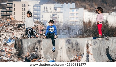Poor kids playing across the garbage and the fire,.
