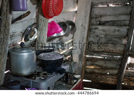 Poor kitchen in the house of worn wooden planks. The kitchen contains only the most necessary equipment like pots, plates, bowls and glasses. Wretched rickety hovel