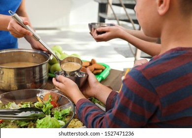 Poor Little Children Receiving Food From Volunteer In Charity Centre, Closeup