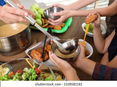 Poor Little Children Receiving Food From Volunteer In Charity Centre, Closeup