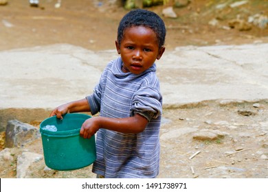 Poor Malagasy Boy Carrying Plastic Bucket - Poverty