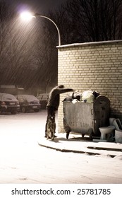 Poor Man Rummaging In Garbage Dumpster On Winter Night