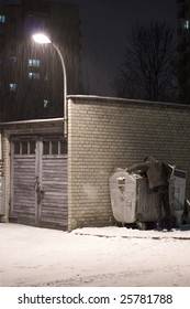 Poor Man Rummaging In Garbage Dumpster On Winter Night
