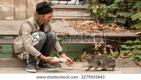 Poor man sharing food with homeless cat outdoors