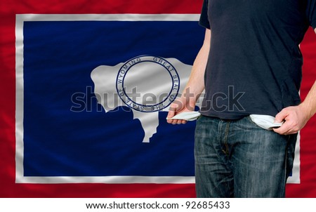 poor man showing empty pockets in front of wyoming flag